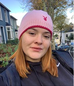 Head shot of young white woman wearing a pink knitted hat