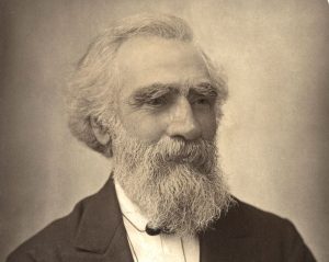 Black and white, sepai toned photo of beared man, known to be John Passmore Edwards