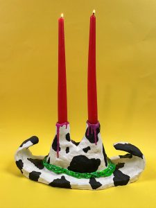 Images shows a brighty painted ceramic candle holder