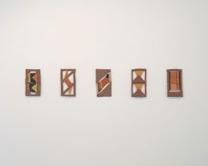 Images shows five peices of ceramics work hanging on a wall