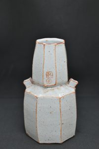 pale tiered ceramic faceted vase with black background