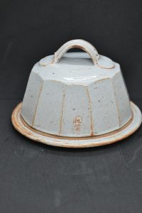 Faceted pale round butter dish with black background
