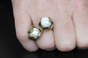 Close up hand modelling double pearl brass ring.