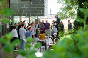 Image shows a group of people gathered outside Newlyn Art Gallery listening to one man talking