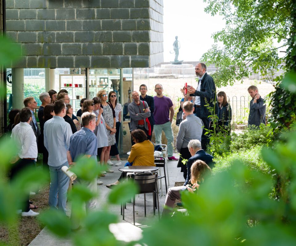 Image shows a group of people gathered outside Newlyn Art Gallery listening to one man talking