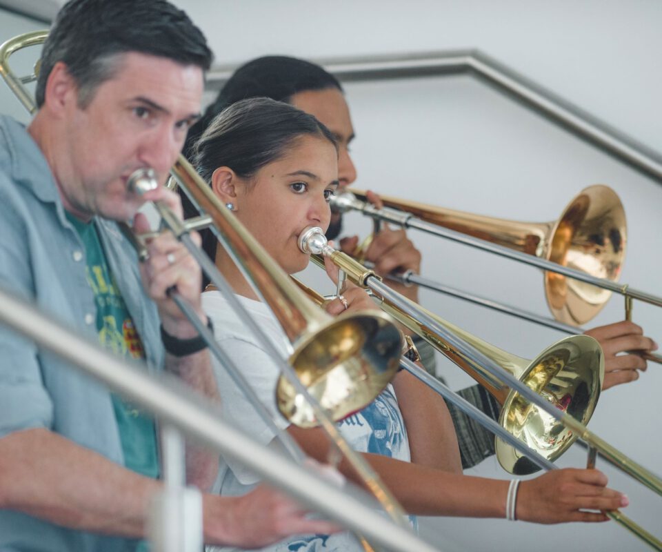 Image shows a group of musicians playing trombones