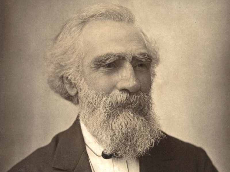 Black and white, sepai toned photo of beared man, known to be John Passmore Edwards