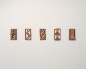 Images shows five peices of ceramics work hanging on a wall