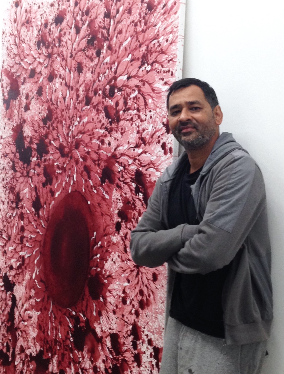 Imran Qureshi standing beside on of his paintings for The Exchange in Penzance