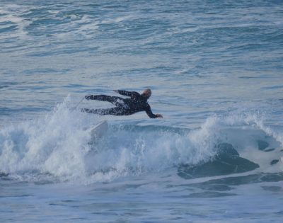 Man in the sea, big wave, falling off surf board