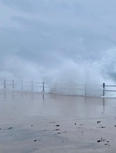 Image shows waves crashing over railings onto Penzance Promenade