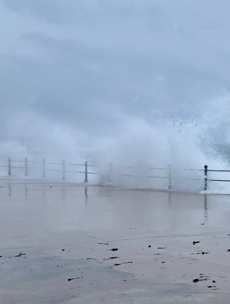 Image shows waves crashing over railings onto Penzance Promenade