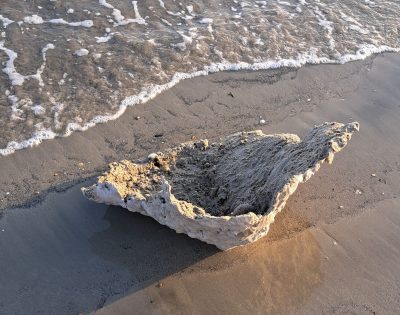 Image shows a cast of sandcastle lying on a sandy beach