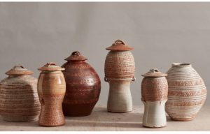 Image shows a line up of several brown ceramic pots