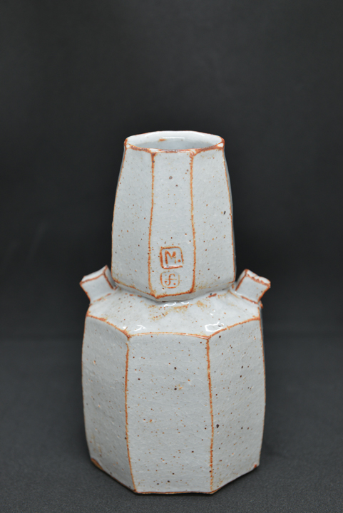 pale tiered ceramic faceted vase with black background