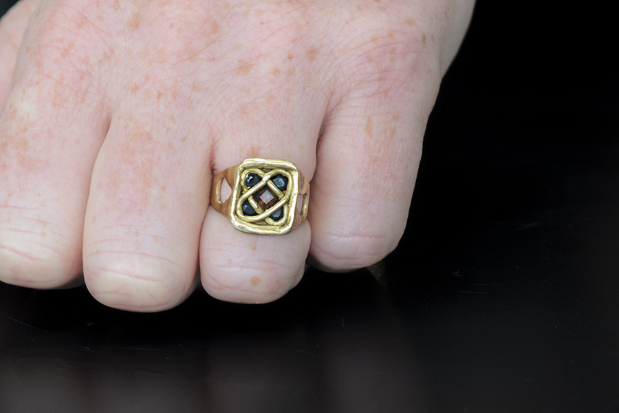Close up of hand modelling Sonnet Ring with Sapphire & Tormolin on black background