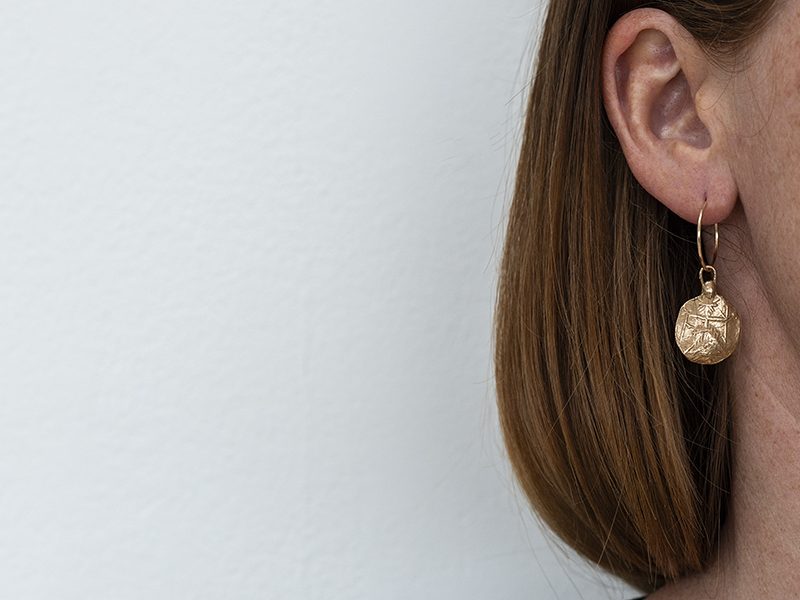 Close up of model wearing brass chain hoop earring.