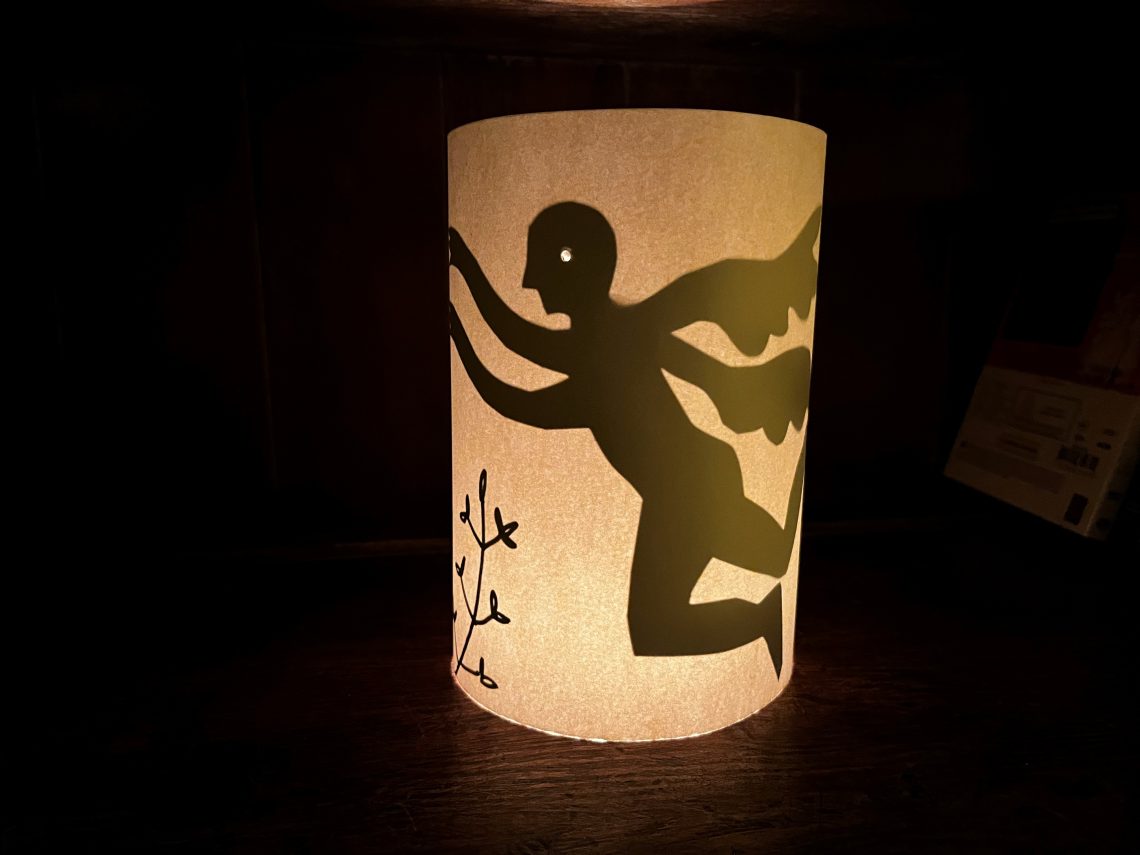 Image shows a lantern lit from inside with a image in shadow