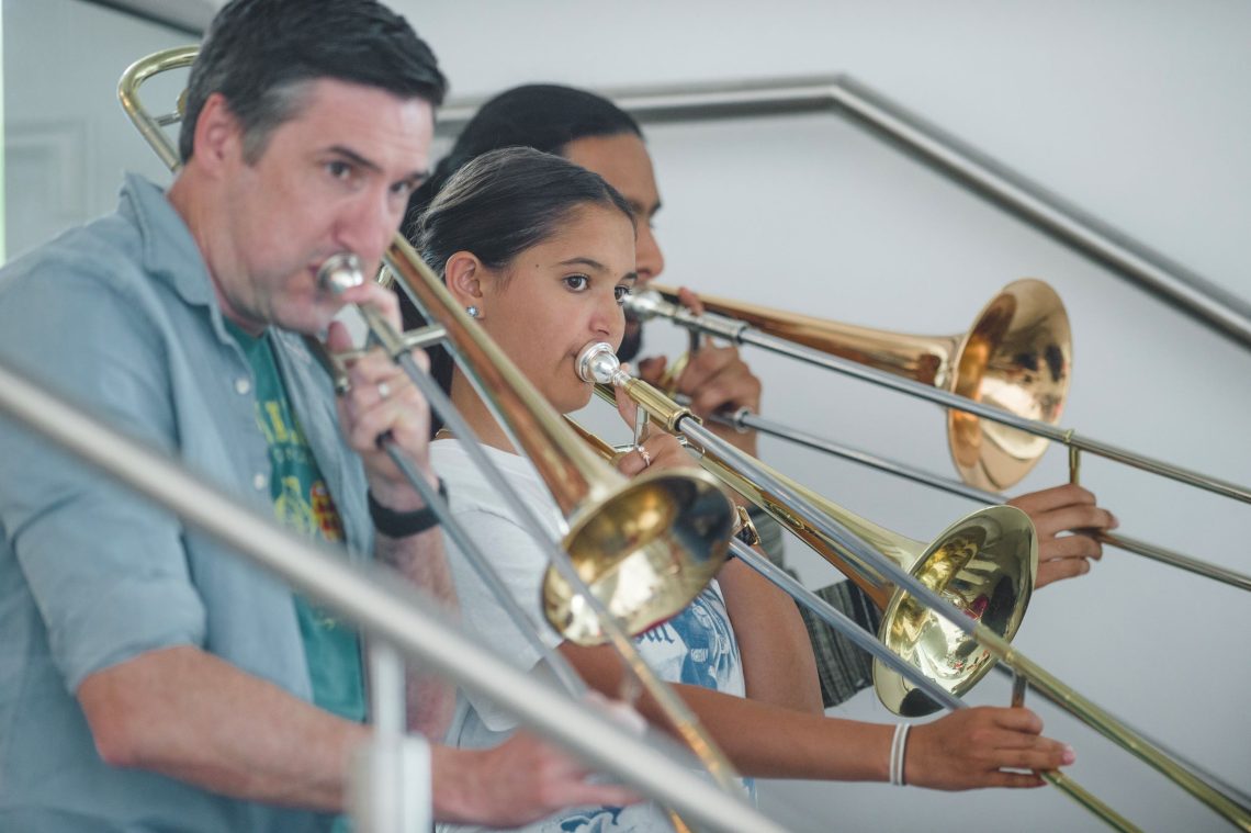 Image shows a group of musicians playing trombones