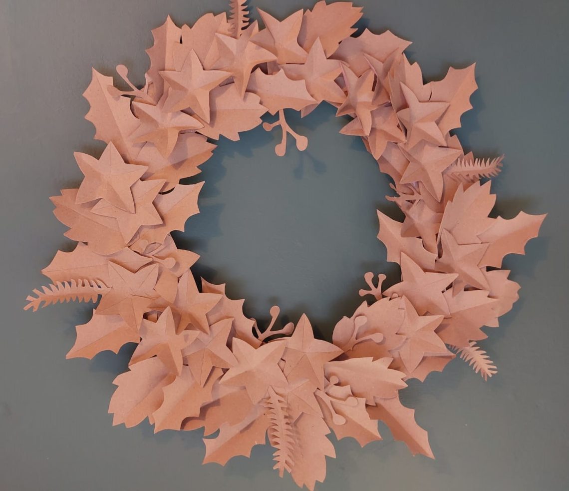 Image shows paper leaf cut outs to make a Christmas wreath