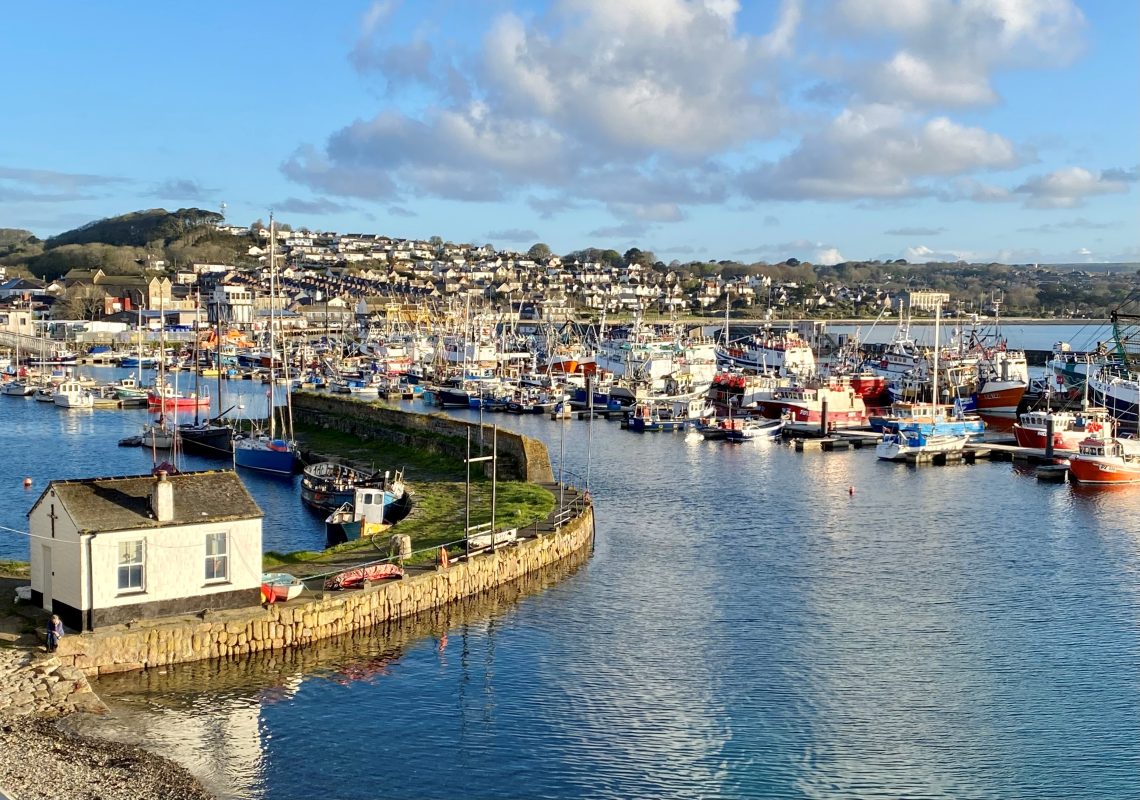 Images hows the old harbour in Newlyn with the modern piers in the background