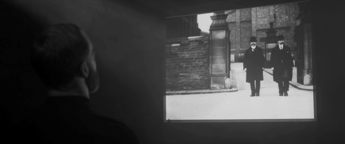 Image shows someone wathcing an old black and white film depicting two policeman